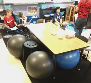 An image of a communal desk in a classroom with exercise balls for seats.